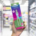 A person's hand holding up a box of ZAMED Terra Trust eco pregnancy test in a store aisle. The box is prominently green and purple with text highlighting the product as 'ultra early,' '0% plastic' and '99% accurate.